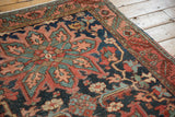 Oversized leaves and vinery in dusty navy, coral, and teal on antique Heriz pile.