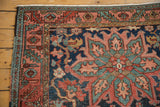 Antique Heriz rug corner: serrated border, dusty navy field, oxidized green vinery.