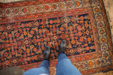 Vintage Malayer rug's navy Herati motif, red floral border, showing wear.