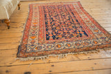 Vintage Persian Malayer rug border featuring red, tangerine, saffron floral blossoms and frayed fringe.