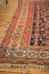 Malayer rug's wide border: red, orange, and sand floral blossoms, with visible pile wear.