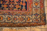 Corner of vintage Malayer rug with richly colored floral and germinating plant motifs, and fringe.