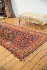 Wide floral border detail of a vintage Malayer rug, with navy Herati motif and fringe.