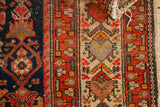 Vintage Malayer rug detail: red floral border, navy Herati pattern, showing even wear.