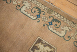 Vintage Chinese rug corner with beige shield motif and stylized teal, sapphire blue border.