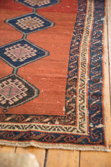 Navy blue running wave border and abrashed madder red field of an antique Bakshaish rug.