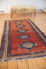 Antique Bakshaish rug with a central column of diamond medallions shown from a full-length, angled perspective.