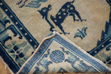 Peking rug corner revealing hand-knotted back, pictorial deer motif, and visible pile wear.