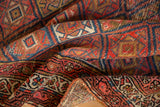 Folded edge of Kurdish Malayer rug, showing madder red geometric guls, boteh border, and woven back.