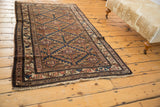 Hand-knotted end of antique Hamadan rug, showing natural fringe and worn germinating plant motifs.
