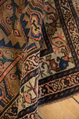 Antique Hamadan rug's hand-knotted pile, showing serrated outlines and germinating plants in sand, blue, pink.