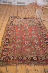 Tattered fringe, charcoal brown border with blush and gold geometric patterns on an antique Bijar rug.