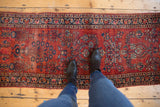 Vintage Mohajeran Sarouk runner segment with ruby red floral sprays and visible even wear.