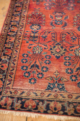 Corner detail of vintage Sarouk rug with ruby red field, navy floral border, and visible foundation.