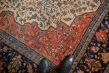 Farahan Sarouk rug corner: wide terracotta main border, navy reciprocating pawn, and even wear.