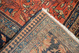 Folded corner of antique Farahan Sarouk rug showing terra cotta pile, pawn border, fringe, and hand-knotted foundation.