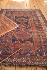 Antique Afshar rug detail: navy field, madder red hook and latch, floral palmette motifs.