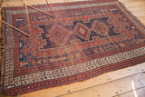 Intricate geometric border on Antique Afshar rug in madder red, navy, ivory, and tattered fringe.