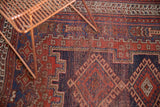 Textured pile of antique Afshar rug, showing madder root red, navy geometric motifs, floral palmettes.