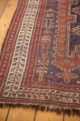 Antique Afshar rug border with madder red, ivory, and navy geometric patterns, showing tattered fringe.