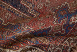Detailed texture of an antique hand knotted Afshar rug with madder red, navy blue tribal motifs and wear.