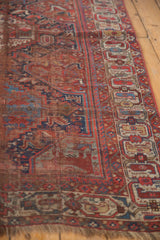 Lower corner of antique Qashqai rug, with fringed edge and tribal motifs in red, blue, and ivory.