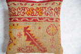 Hand-knotted antique rug fragment pillow, close-up of muted red and gold geometric patterns.