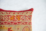 Antique rug fragment pillow with vibrant red binding and textured geometric patterns.
