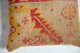 Textured hand-knotted weave with red and golden geometric motifs on the antique rug fragment pillow.