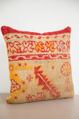 Textured lower edge of hand-knotted rug fragment pillow, red and yellow geometric pattern.