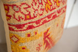Detailed view of antique rug fragment pillow with hand-knotted red, gold, and beige geometric design.