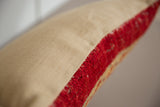 Detail showing the pillow's finely woven beige fabric and plush red antique rug fragment.