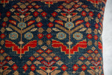 Hand-knotted vintage rug fragment pillow, dense tribal pattern in blue, red, and tan.