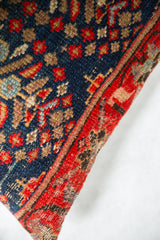 Intricate hand-knotted pattern on vintage rug fragment pillow in deep navy, ruby red, and natural beige.