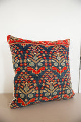 Hand-knotted vintage rug fragment pillow showcasing red, indigo, and earth tone floral pattern.
