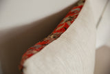 Vintage rug fragment pillow edge, rich red pattern, and natural linen backing.