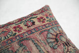 Antique Persian Kerman rug fragment pillow featuring intricate floral motifs in faded madder red and dusty blue.