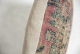 Pillow edge close-up: Faded red and blue rug fragment with textured beige backing.