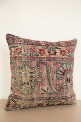 Textured antique rug fragment pillow showcasing muted red, blue, and beige curvilinear motifs.