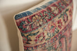 Antique rug fragment pillow detail showing hand-knotted weave and soft red, blue floral design.