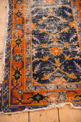 Tattered edge of vintage Chinese Hamadan rug with worn tangerine palmette border and cobalt field.