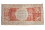 Vintage distressed Oushak rug with a roundel medallion on an abrashed raspberry red and ivory field.
