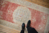 Even wear and low pile texture of a distressed Oushak rug, with feet for scale.