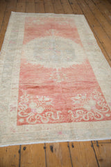 Angled view of a distressed Oushak rug showing the soft, abrashed texture in raspberry and silver.