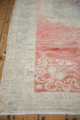 The hand-knotted texture and intact side cord of a vintage distressed Oushak rug's corner.