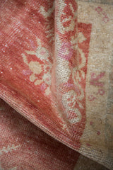 Textured low pile of a distressed Oushak rug, with visible knot heads in dusty red and ivory.