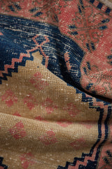 Distressed vintage Oushak rug pile texture with navy, blush, and sand geometric patterns.