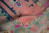 Close-up of distressed vintage Oushak pile with rose, mint, and bright pink motifs.