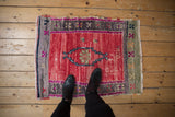 Abrashed red field and patterned magenta and gray borders of a distressed Oushak rug.
