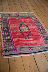 Distressed Oushak rug corner with abrashed red pile, geometric border, and light fringe.